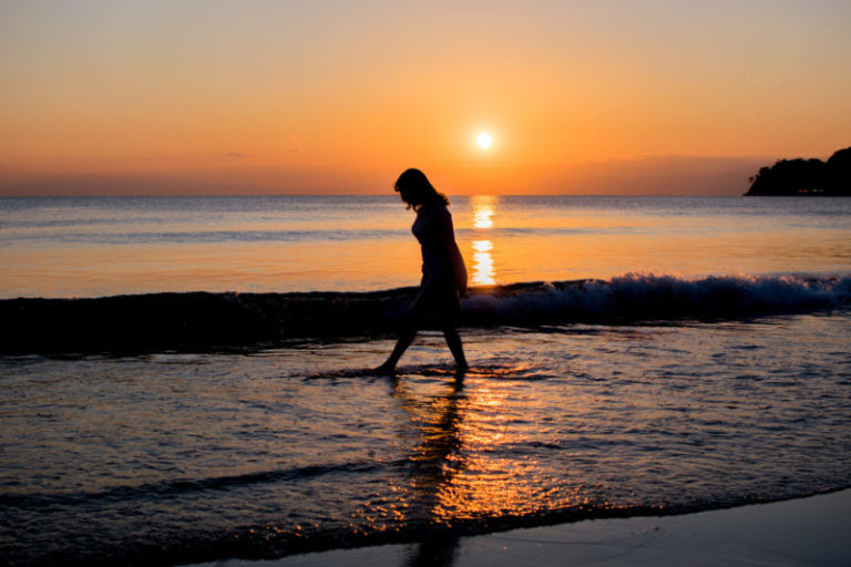 夕日の海岸を歩く女性